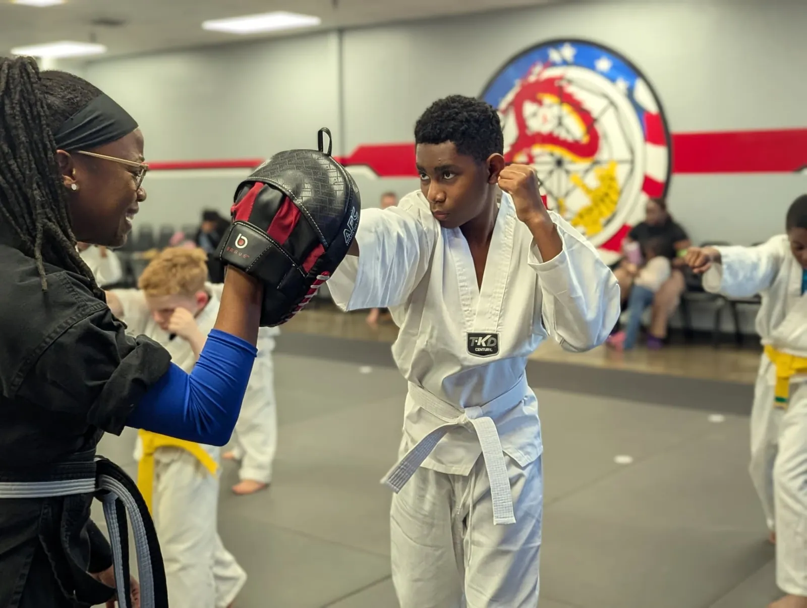 Instructor holding a pad as a young student strikes